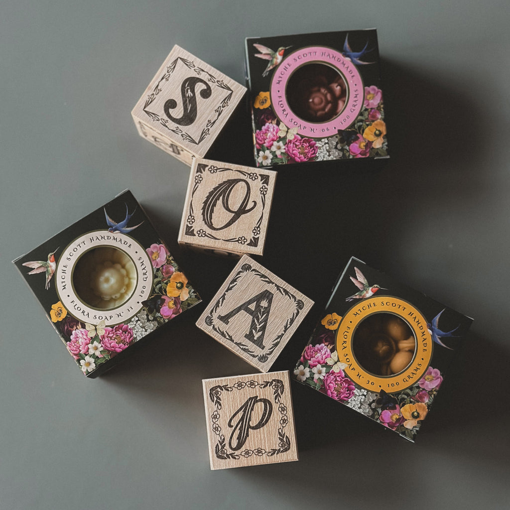 Set of decorative boxes with floral designs and monograms on a dark surface