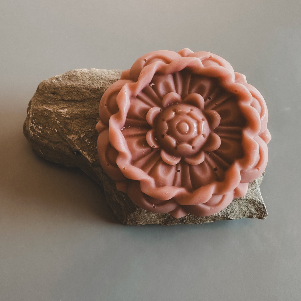 Pink flower-shaped soap on a stone surface