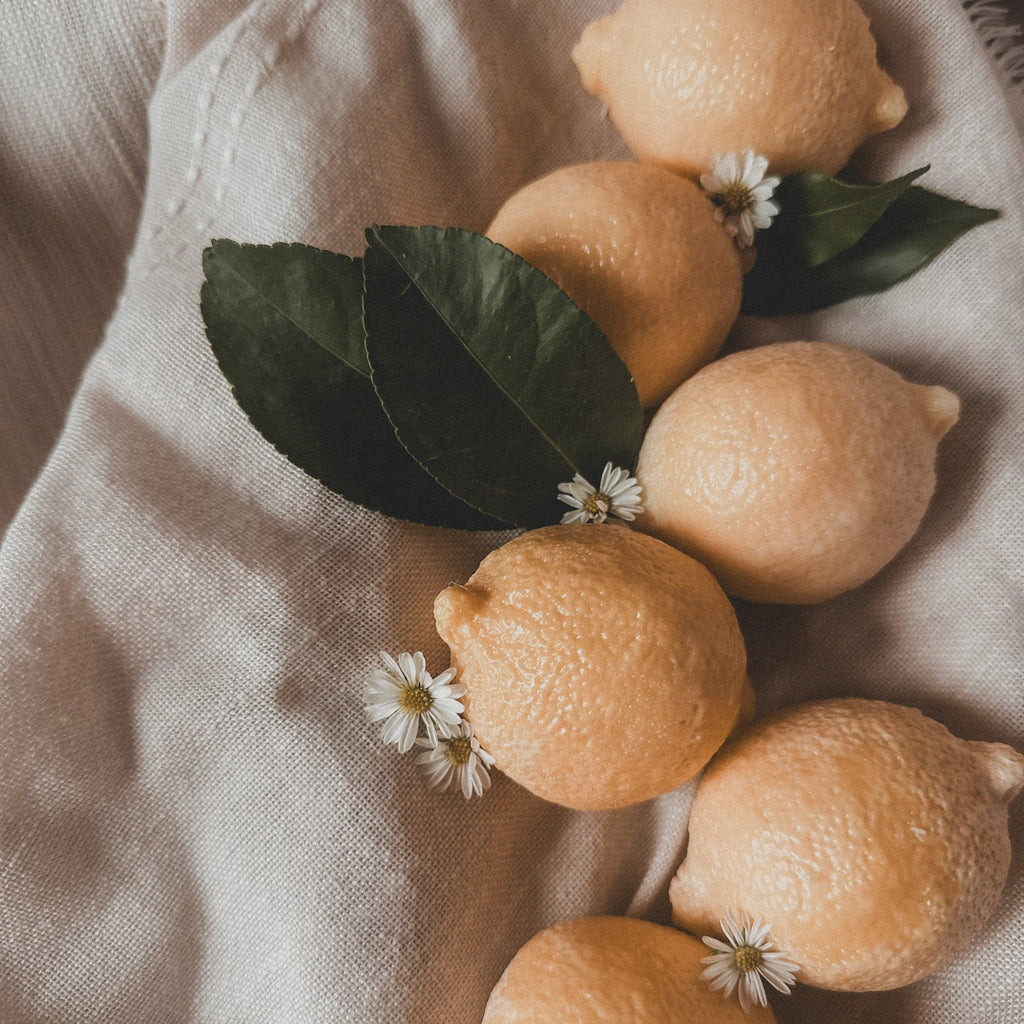 Lemons with leaves and small flowers on a textured fabric surface