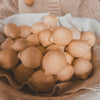 Bowl of round, brown pastries on a textured surface with a beige sweater in the background.