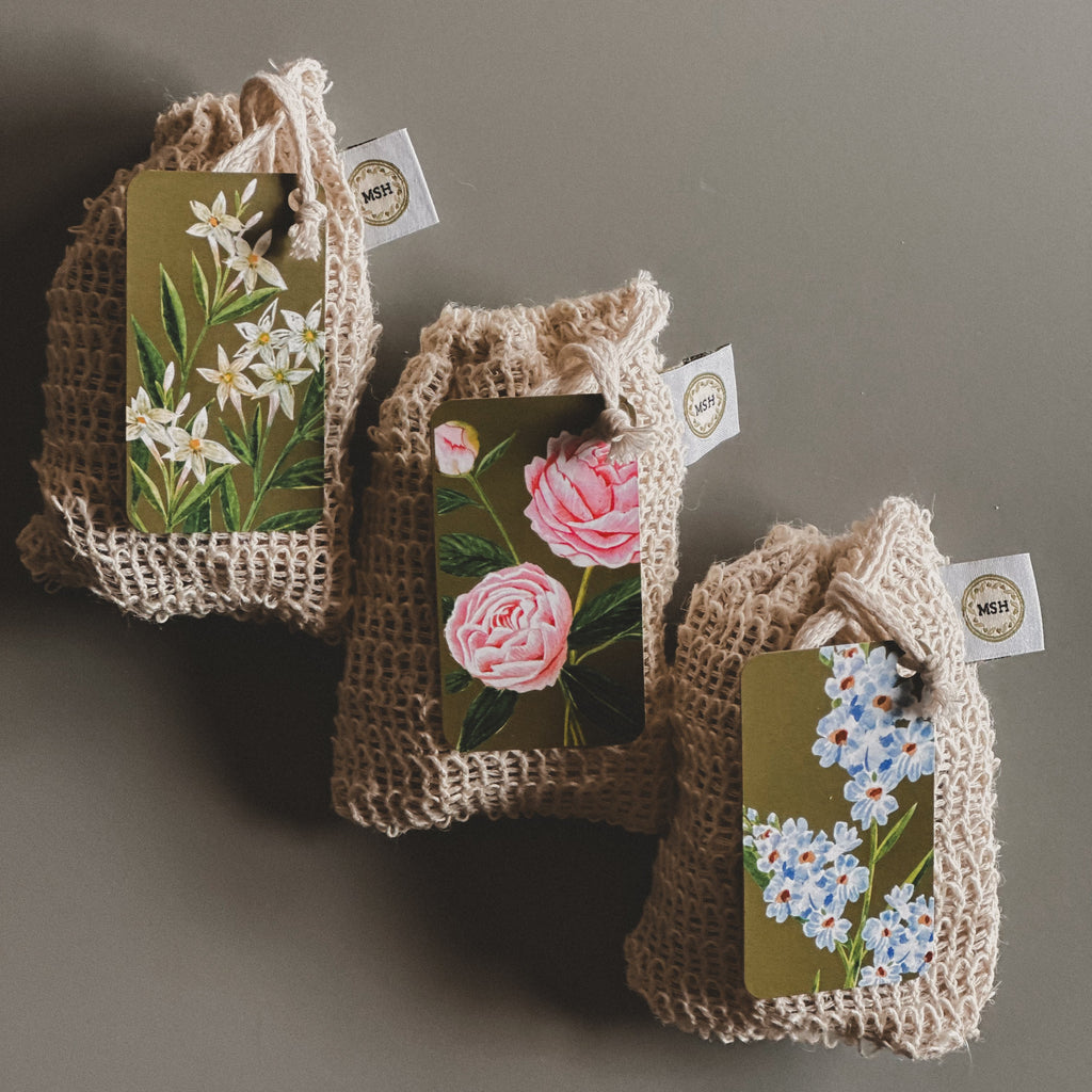 Three small woven bags with floral tags on a gray background