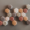 Hexagonal cookies in various colors arranged on a brown surface