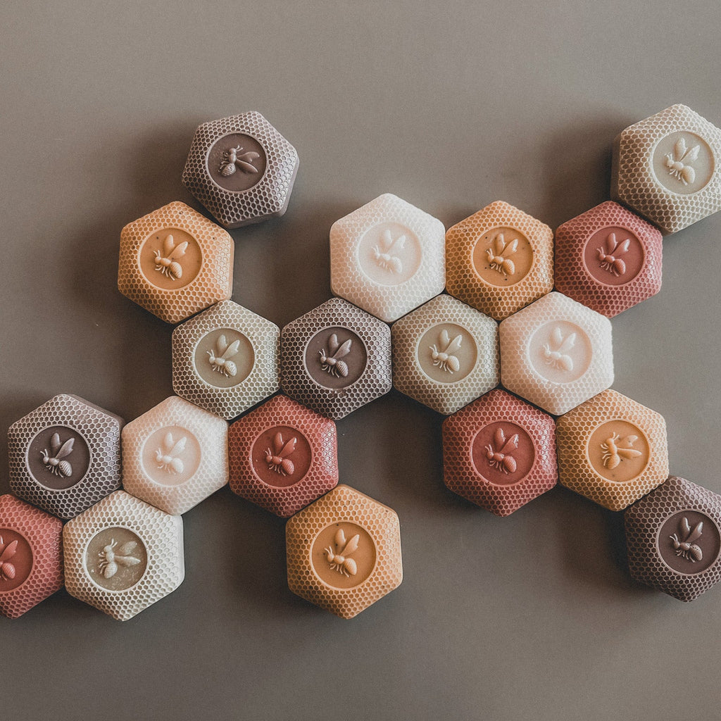 Hexagonal cookies in various colors arranged on a brown surface