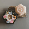 Hexagonal soap with floral design and text on a gray background