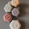 Hexagonal honeycomb-shaped soaps with paw print design on a gray background