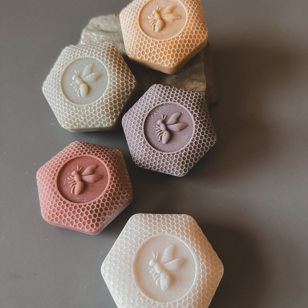 Hexagonal honeycomb-shaped soaps with paw print designs on a gray background