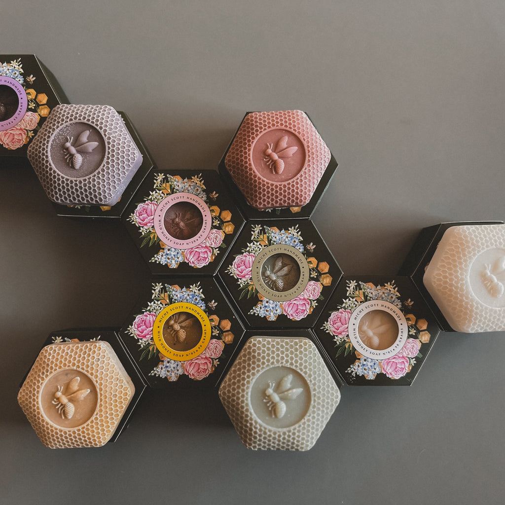 Hexagonal soaps with floral designs and different colors on a gray background